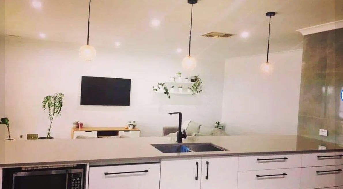 Modern kitchen with pendant lights and wall-mounted TV after electrical fit-out