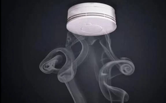 Smoke alarm with curved arms installed on a ceiling
